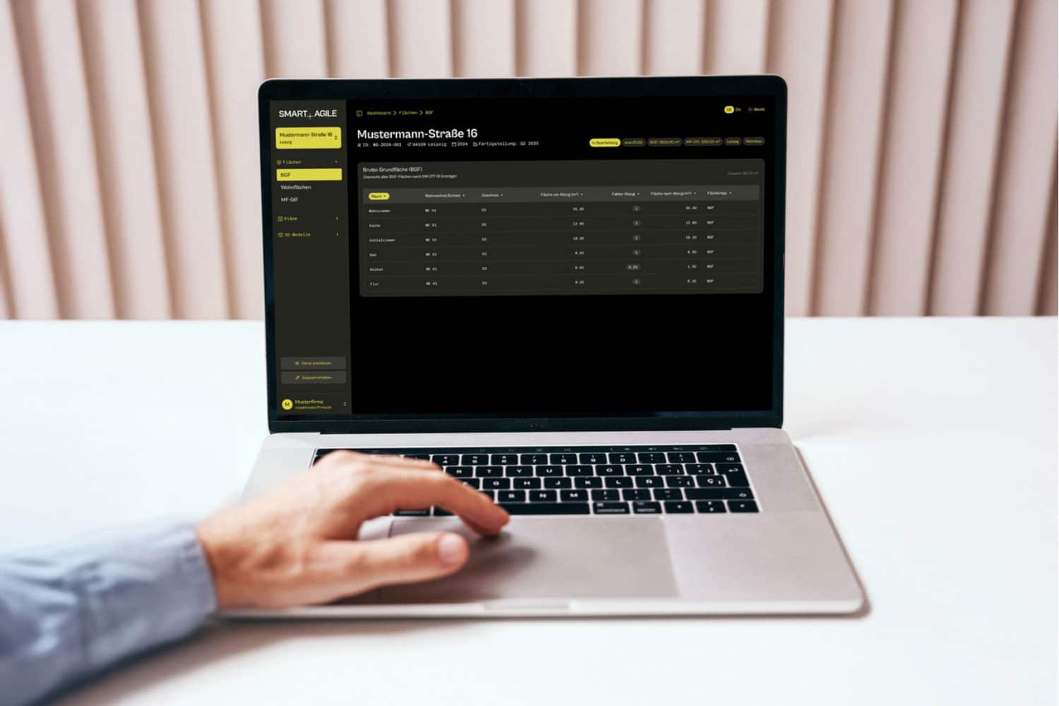 Laptop mit smart+agile Dashboard: BIM-basierte Gebäudedokumentation und BGF-Flächenübersicht für Mustermann-Straße 16.